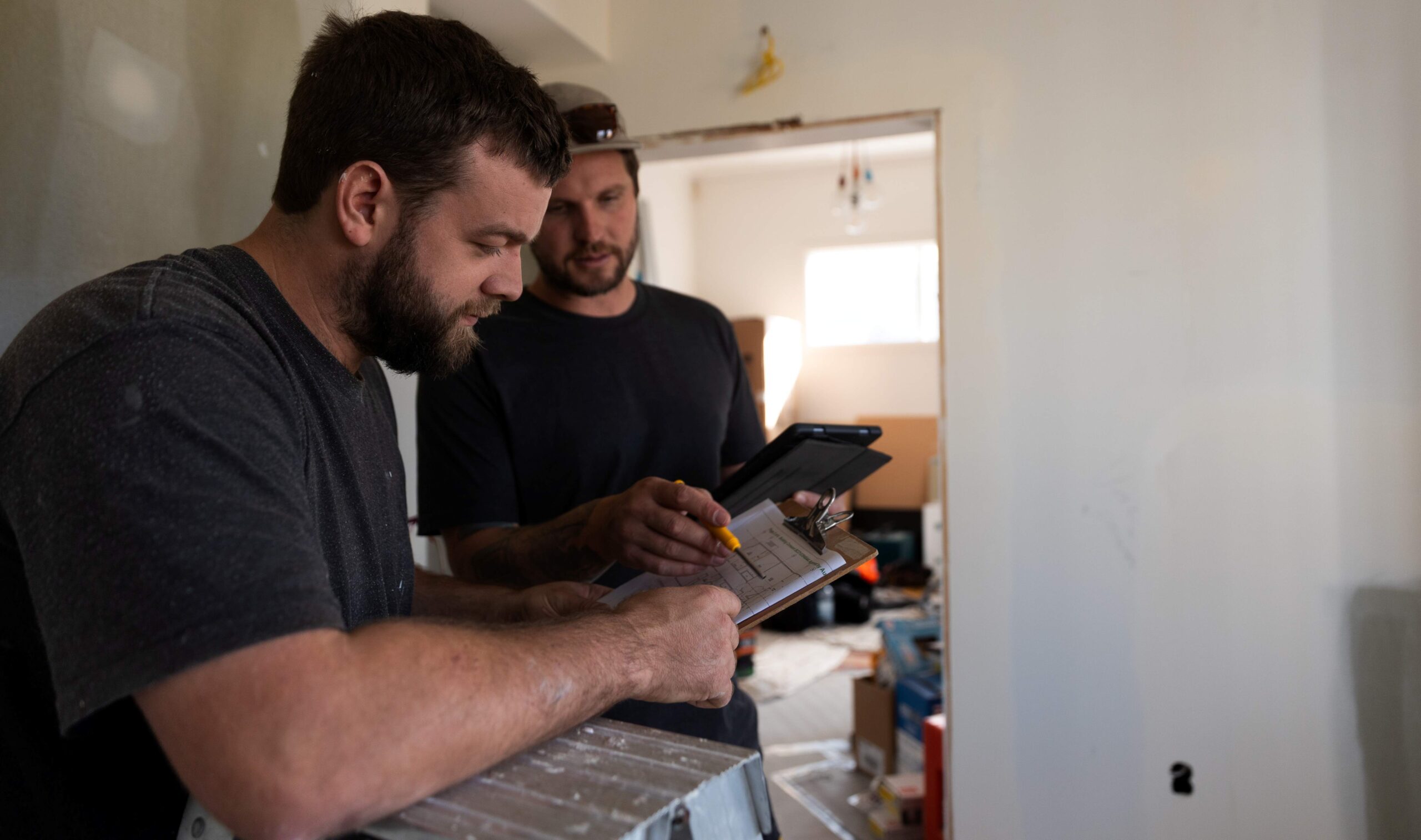 Two men on a construction site checking plans on a clip board