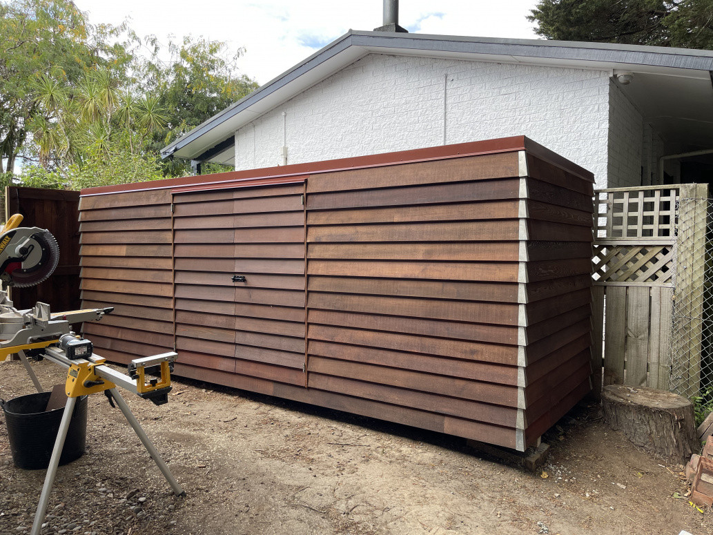 Custom built bike shed to match existing building with cedar weatherboard and scoria corrugated iron roof