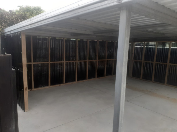 construction of concrete pad and partition walls that enclose the carport