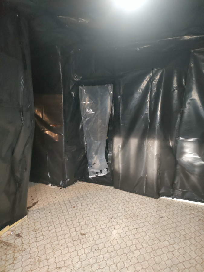 Using black poly plastic to contain the contaminated floor with asbestos tiles to be removed.