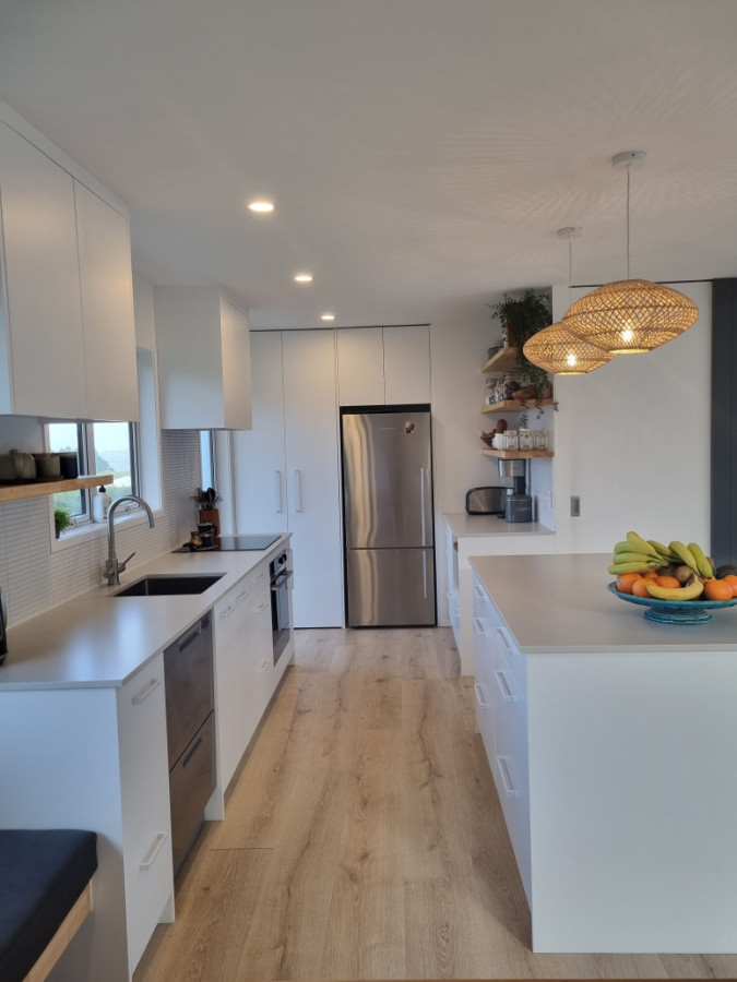 After- Kitchen to Laundry with machines covered by doors. Custom floating shelves