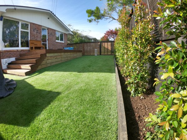 Artificial turf and Eugenia hedges planted + garden edging & base boards along deck.