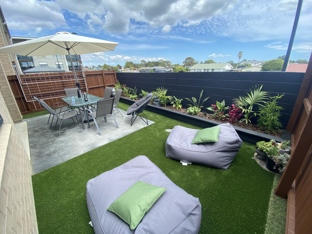 Fully landscaped yard Artificial turf, paving and raised garden bed with planting.