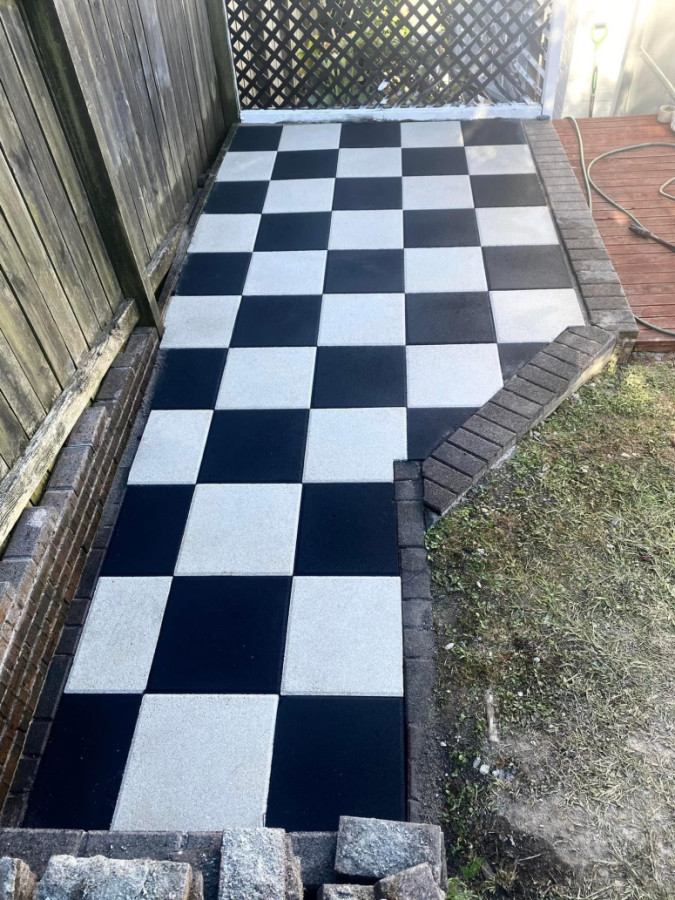 Lovely checkerboard pavers installed with retaining wall along the front of deck.