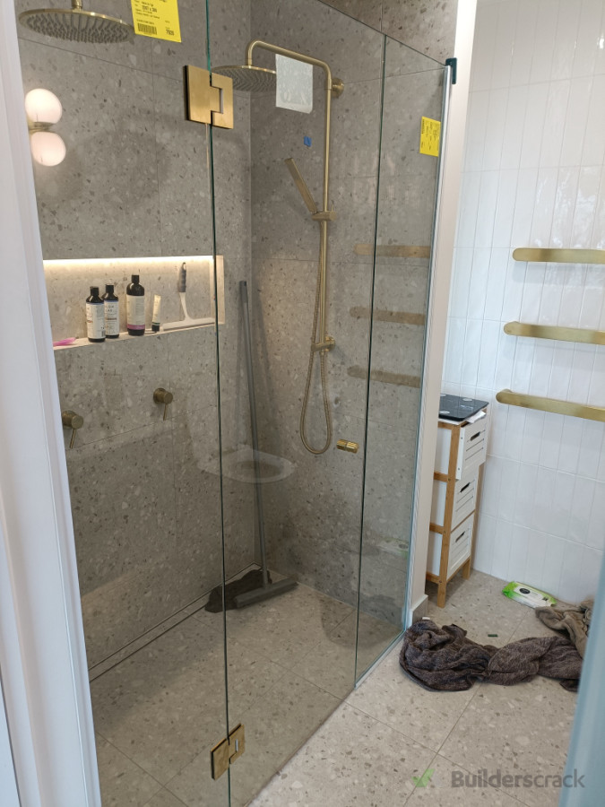 Frameless shower installation with brushed brass hardware