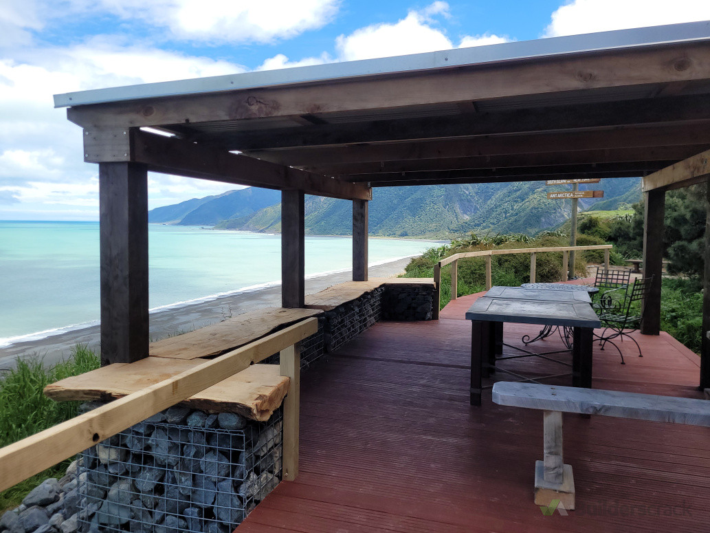 Wharekauhau luxury lodge boardwalk with lookout pergola and deck. Redwood timber framing, Macrocarpa slab seats and posts with gabian baskets