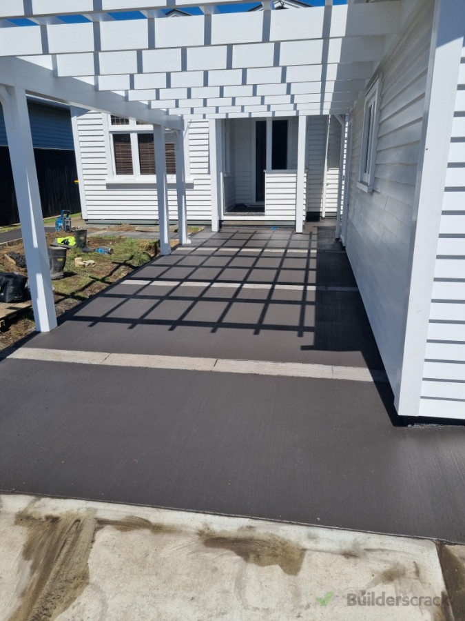 Black concerete driveway, patio and paths with concrete papers place in-situ to look like timber railway sleepers.