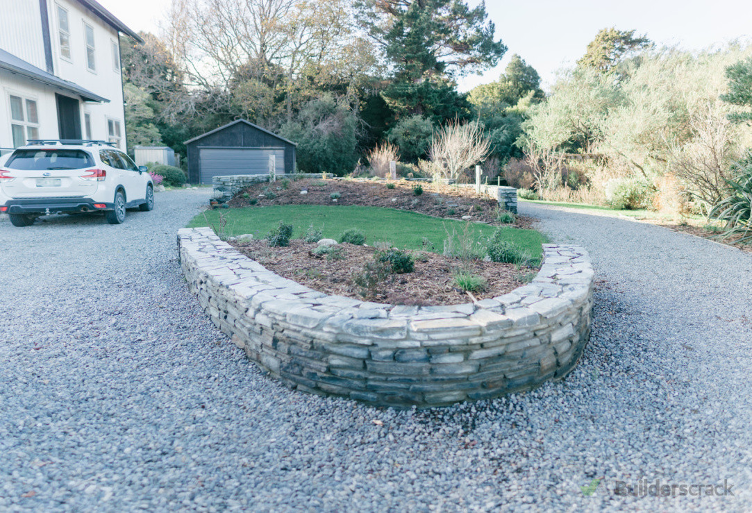 Central Otago  schist stone wall turning circle, pebbled driveway and planted with a selection of florals and natives