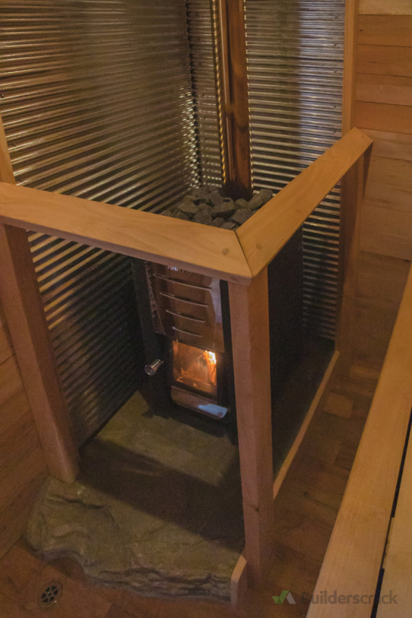 Woodfire sauna stove with custom heat shield and balustrade, oven stone is a giandt schist slab