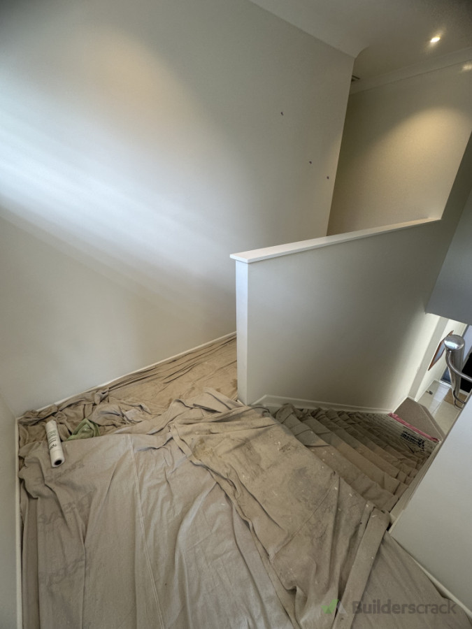 Finishing final topcoats on staircase, ensuring that carpet protected upon painting