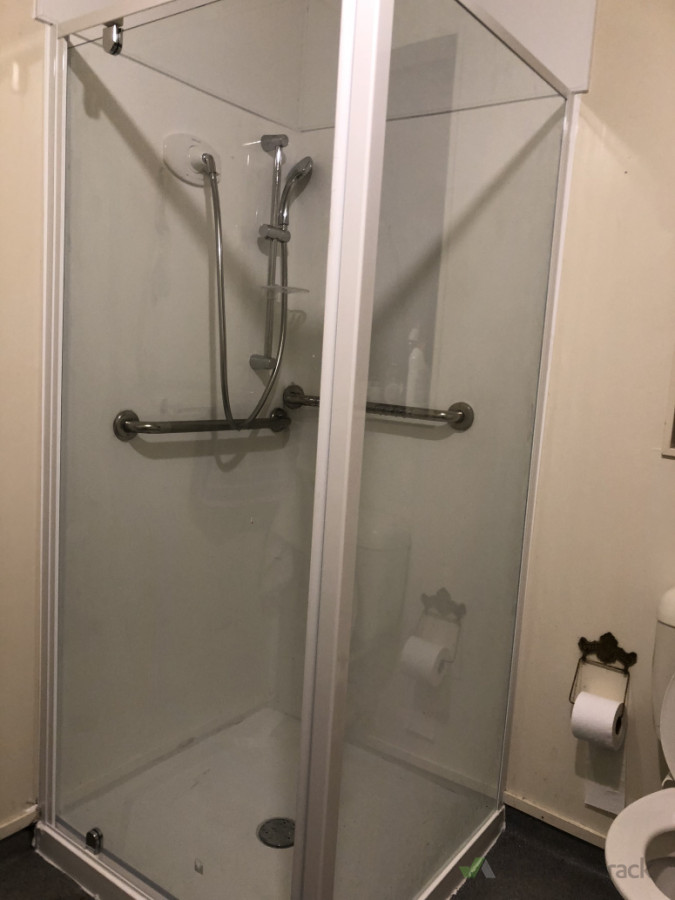 Modern Shower Area - A sleek glass-enclosed shower with stainless steel fixtures, complemented by a neatly arranged bathroom setup.