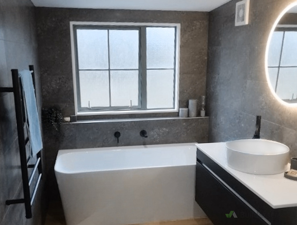 A sophisticated bathroom makeover with a freestanding bath, highlighted by custom tile details, by Direct Tiling