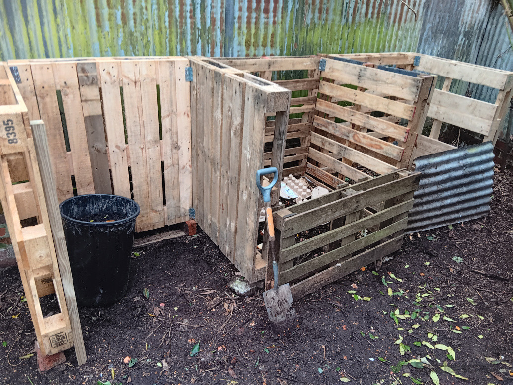 Front view of new composting stalls. Wooden stakes used to secure front of pallets. Costs: Labour,  $80 of materials, and free pallets
