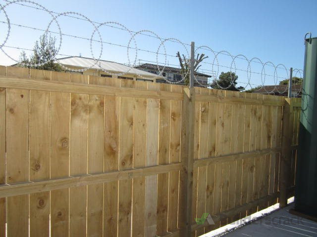 Razor wire on top of the close boarded timber fence