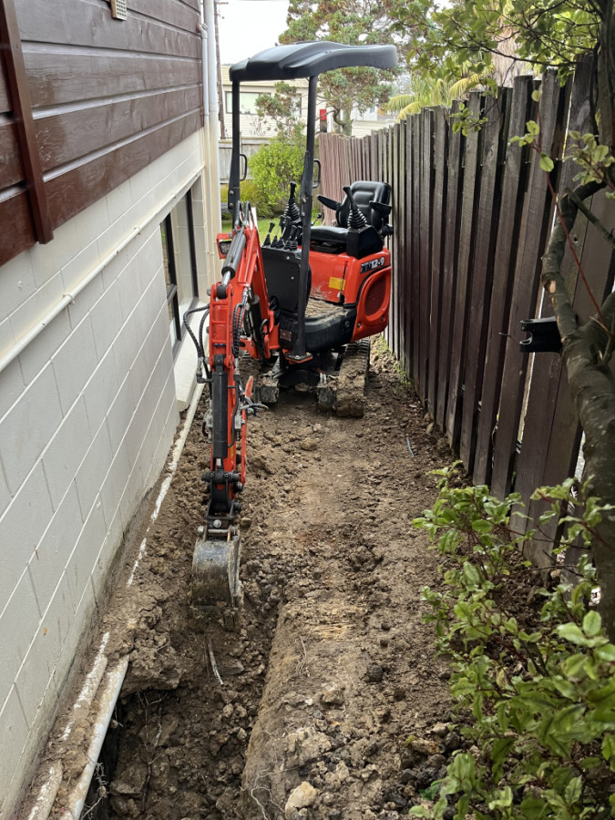 Using our small tight-access machine to dig in behind this block wall and install waterproofing and drainage to fix a flooded minor dwelling. For this job, we squeezed through two 900mm gates — not every project is glamorous, but sometimes playing in the