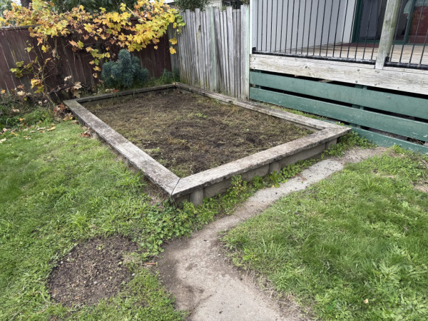 Garden bed prepared for planting, grass planted after wooden pole removal