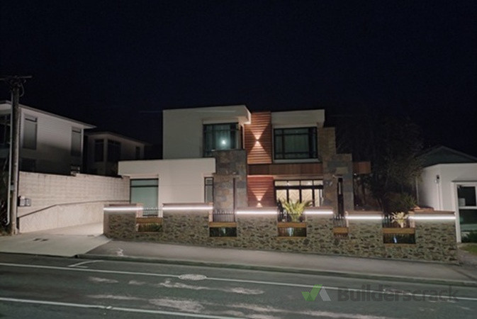 Smart decorative LED tape and spot lights on a residential property masonry fence, controlled by sensors that detect people passing on sidewalk.
