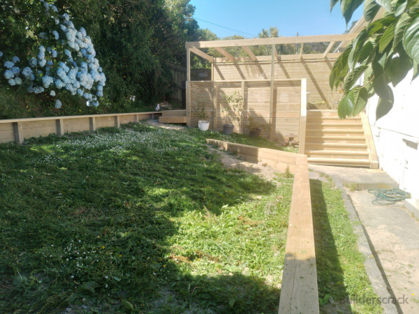 New retaining to support creation of flat lawn area, w/ view of new deck