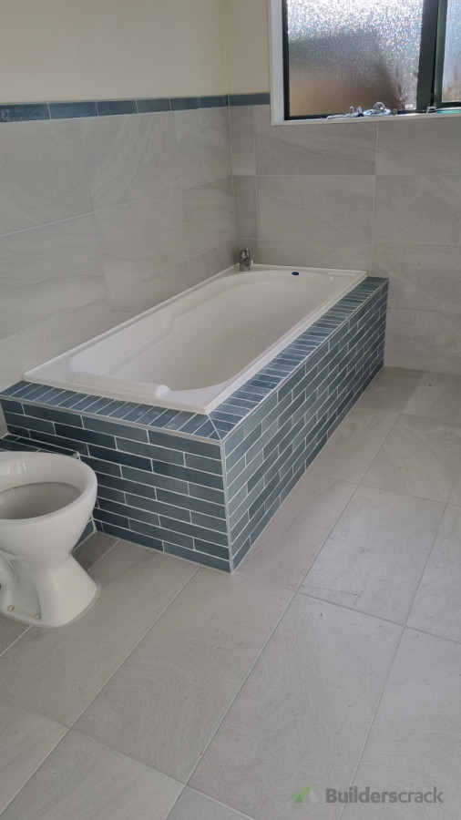 The bathtub front wall features subway tiles grouted with epoxy resin.