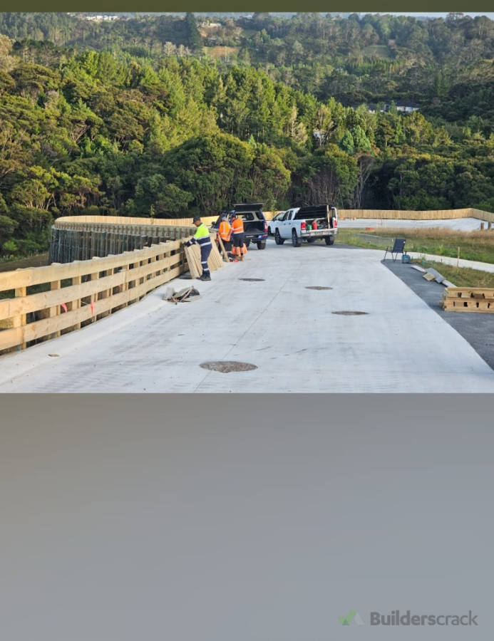 Concrete driveway with wooden handrail being installed for safety.”