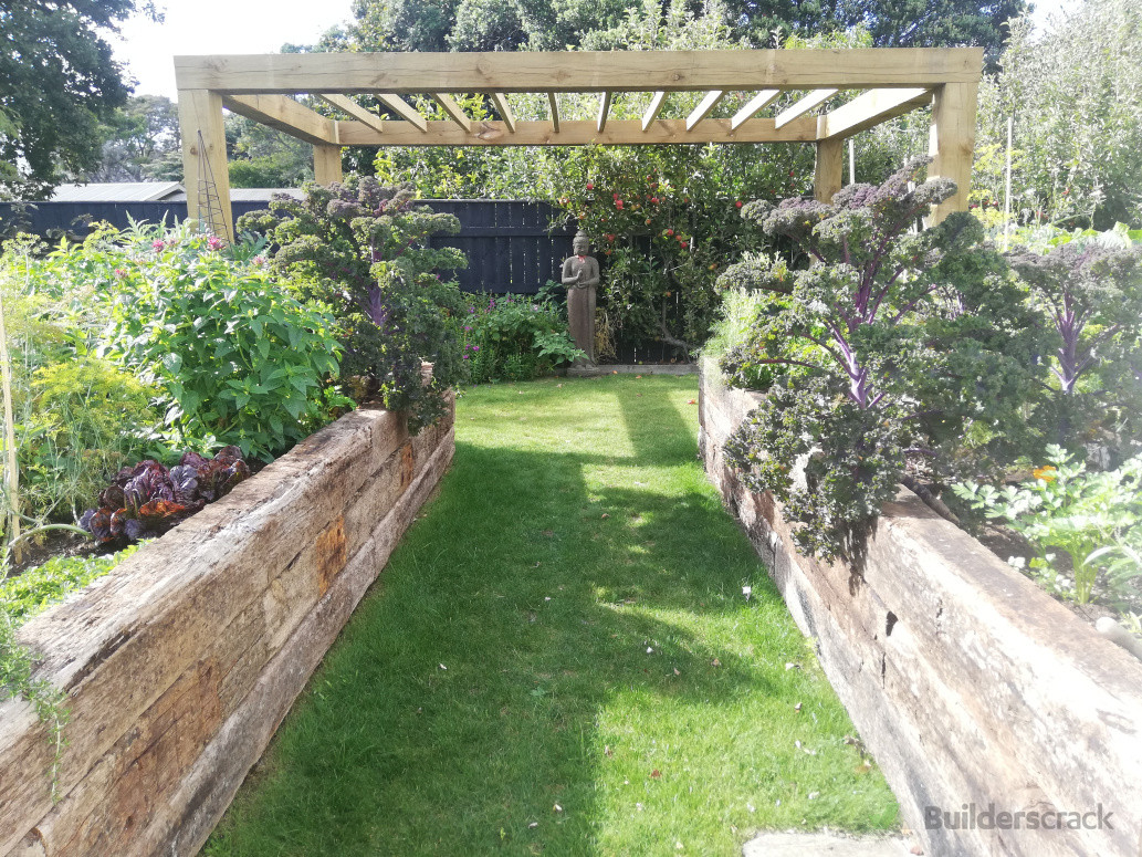 Raised garden beds constructed with hardwood sleepers, complemented by a custom pergola to complete the outdoor space.