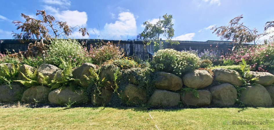 Stacked Large boulder retaining wall with established rock garden