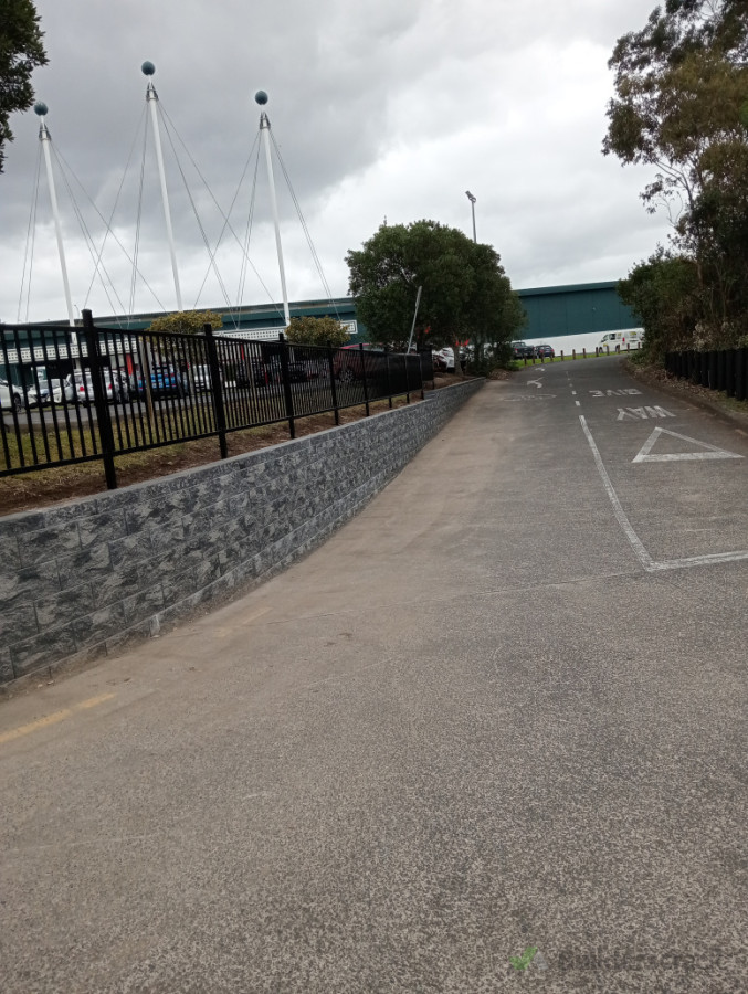 Other side of block retaining wall with fence on top.