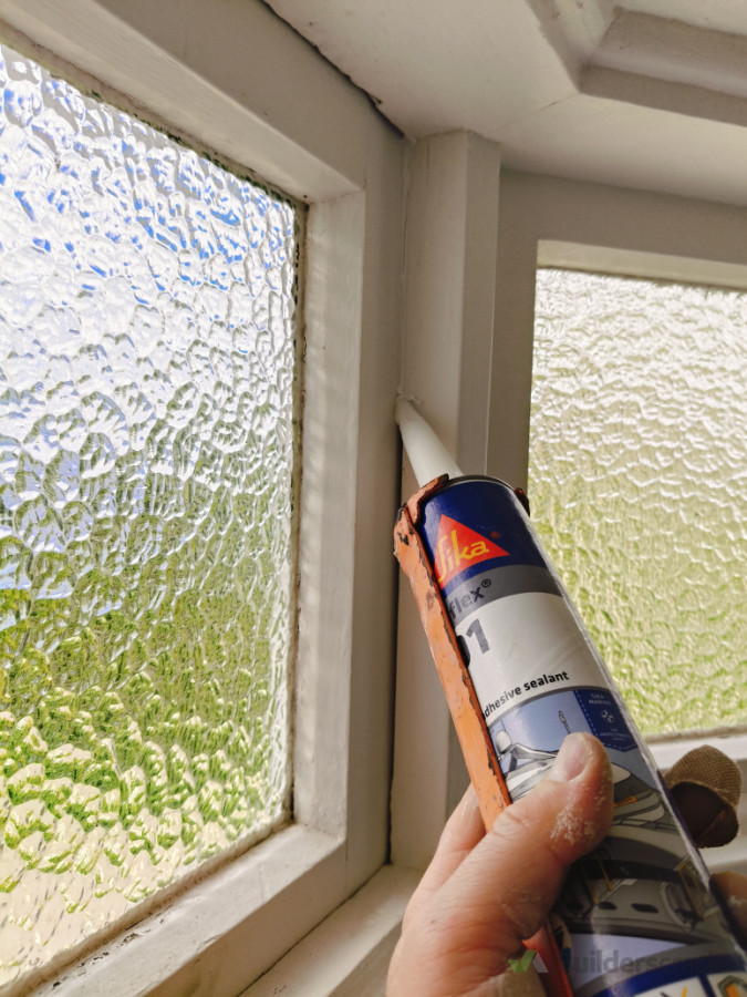 Applying sealant to gaps to block sources of draft and heat loss.