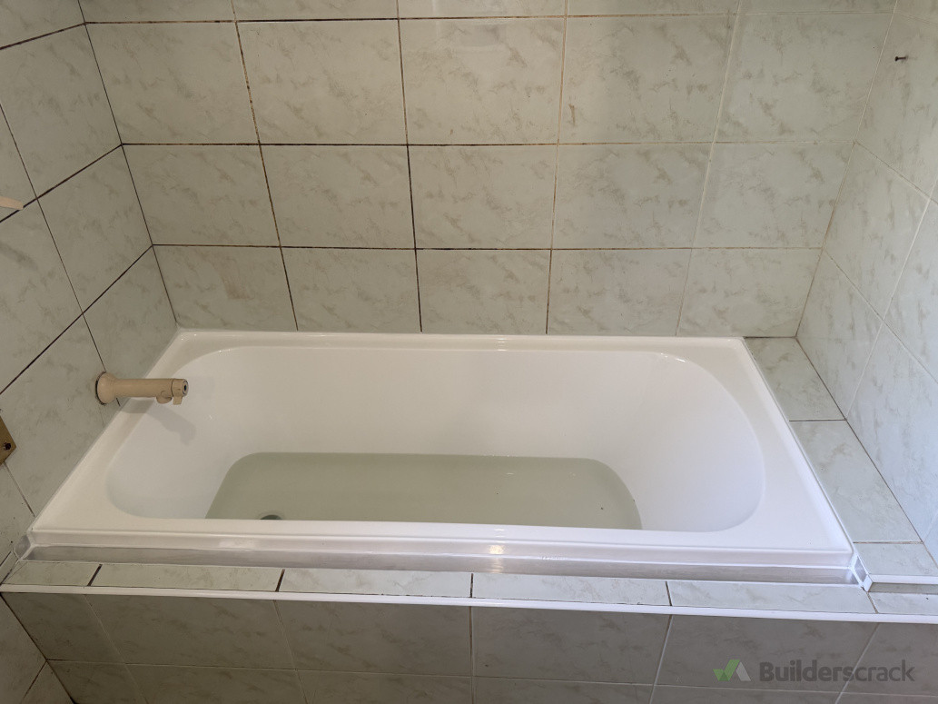 Original bath had a crack, retrofit new bath and frame floor without having to redo tiles