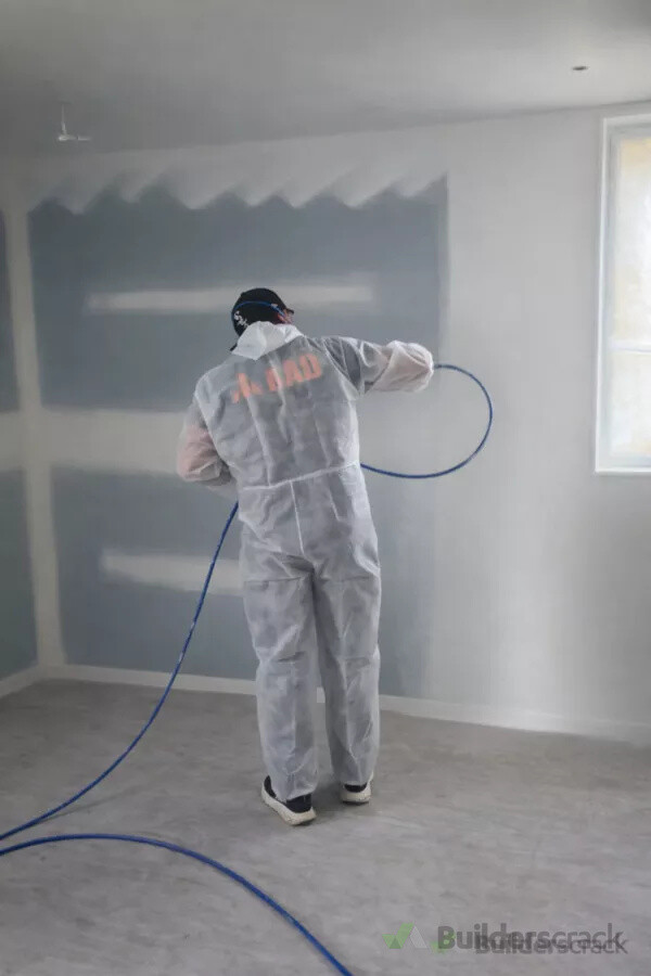 Interior spray painting in progress with surfaces and the surrounding area protected.