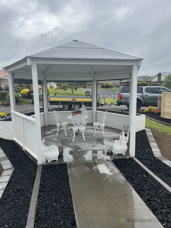Complete outdoor transformation 🔨🌿  A custom freestanding hexagon pergola with a tinted concrete floor, planter boxes on three sides and ground-level garden beds around the edges.  Finished off with a custom ACM panel roof, freshly painted garden struct